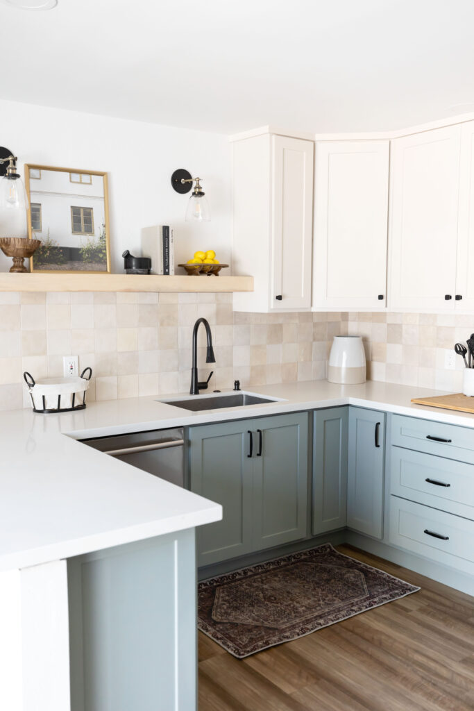 Accessible kitchen in a modern apartment featuring a U-shaped layout with a roll-under sink, two-tone cabinetry in soft green and cream, matte black fixtures, and easy-to-reach open shelving for functional and stylish design.