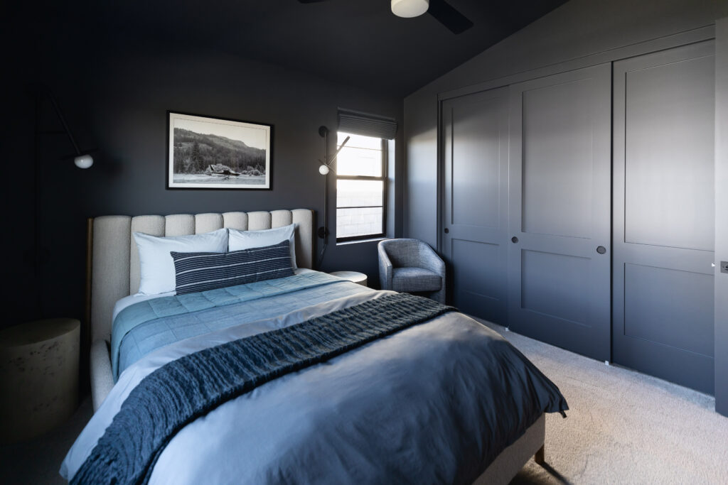 Color drenched bedroom with dark grey walls and luxurious bedding.