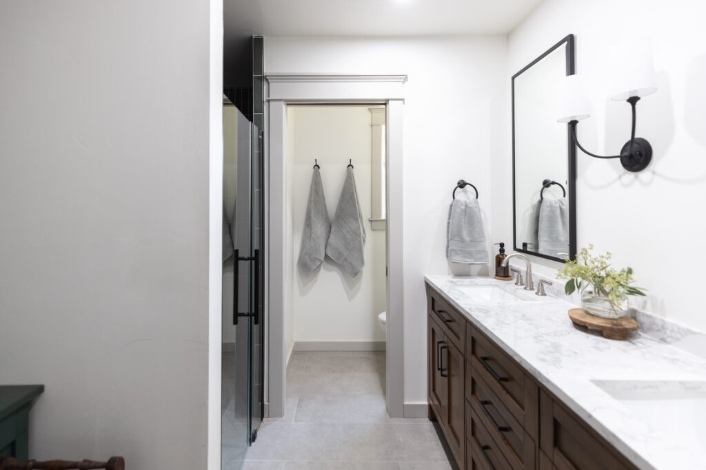 Accessible bathrooms with a curb-less shower, pocket door water closet, dark wood vanity with white countertops. Achieved with a designer and contractor