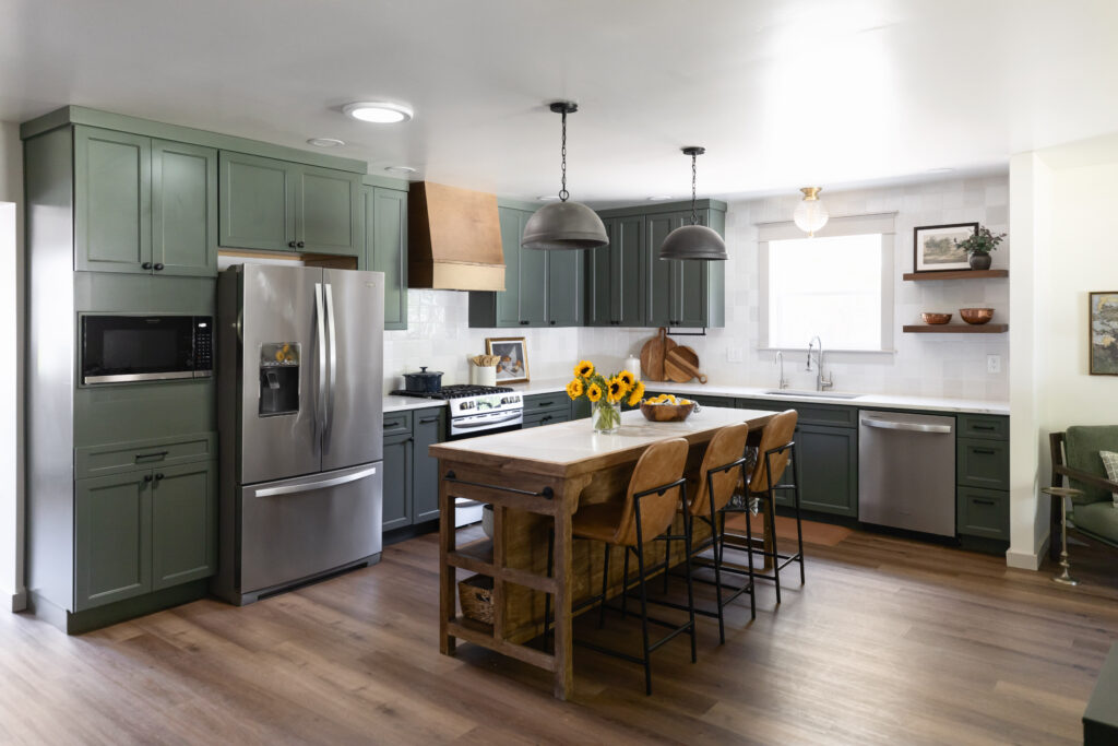 Accessible Barrier Free Design kitchen with green cabinets, wood island, leather barstools, white tile backsplash and grey tile floors. 
