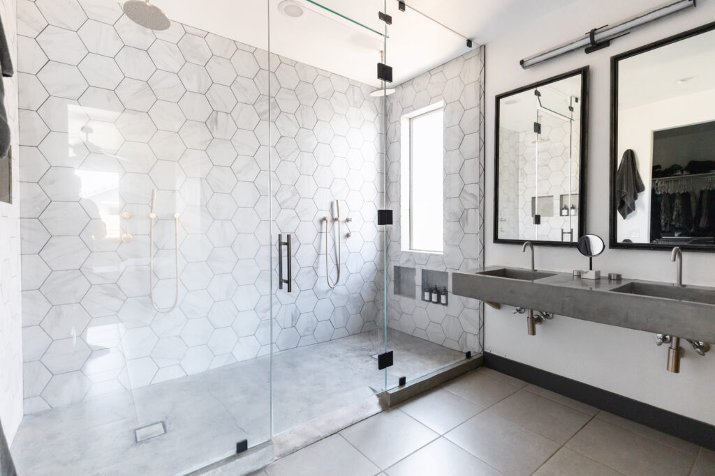 Accessible modern bathroom with roll-in shower, hexagon tile wall, and dual concrete sinks. Nick Lewis talks accessibility. 
